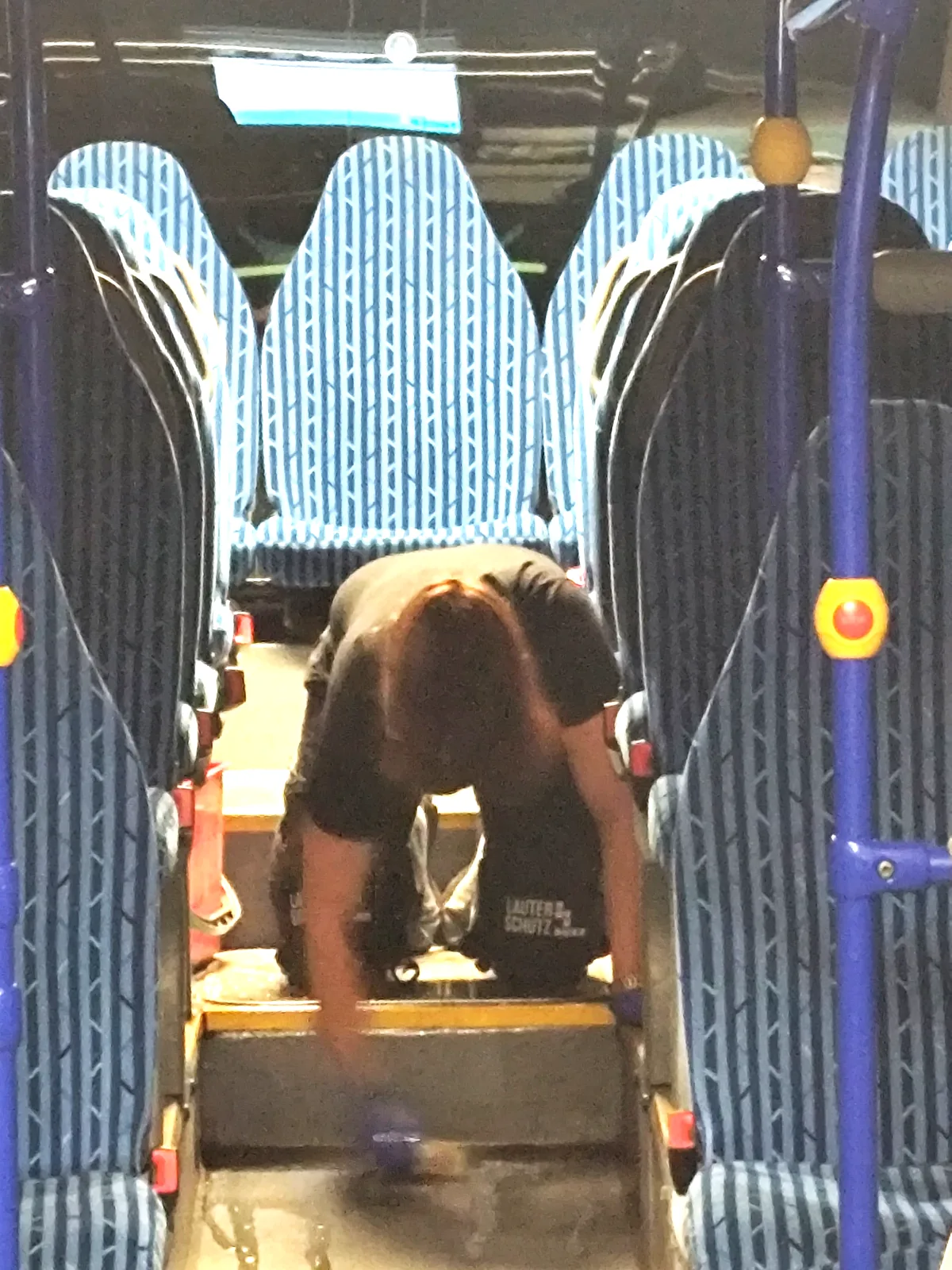 Mitarbeiter der Wilke Reinigung wischt den Mittelgang eines Linienbusses zwischen den Sitzreihen