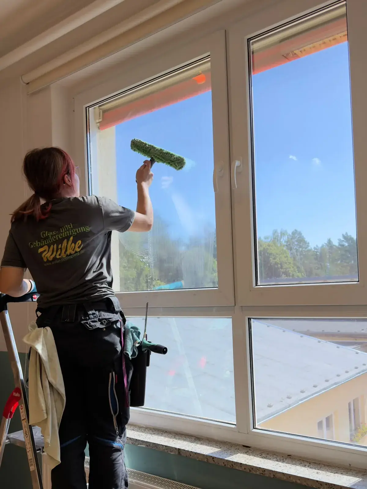 Mitarbeiterin der Wilke Reinigung wäscht eine Fensterscheibe mit dem Einwascher ein