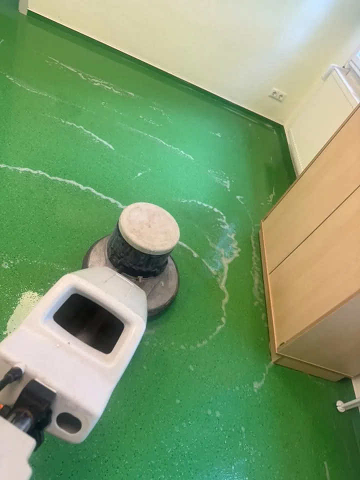 Einscheibenmaschine auf einem grünen Bodenbelag während der Grundreinigung