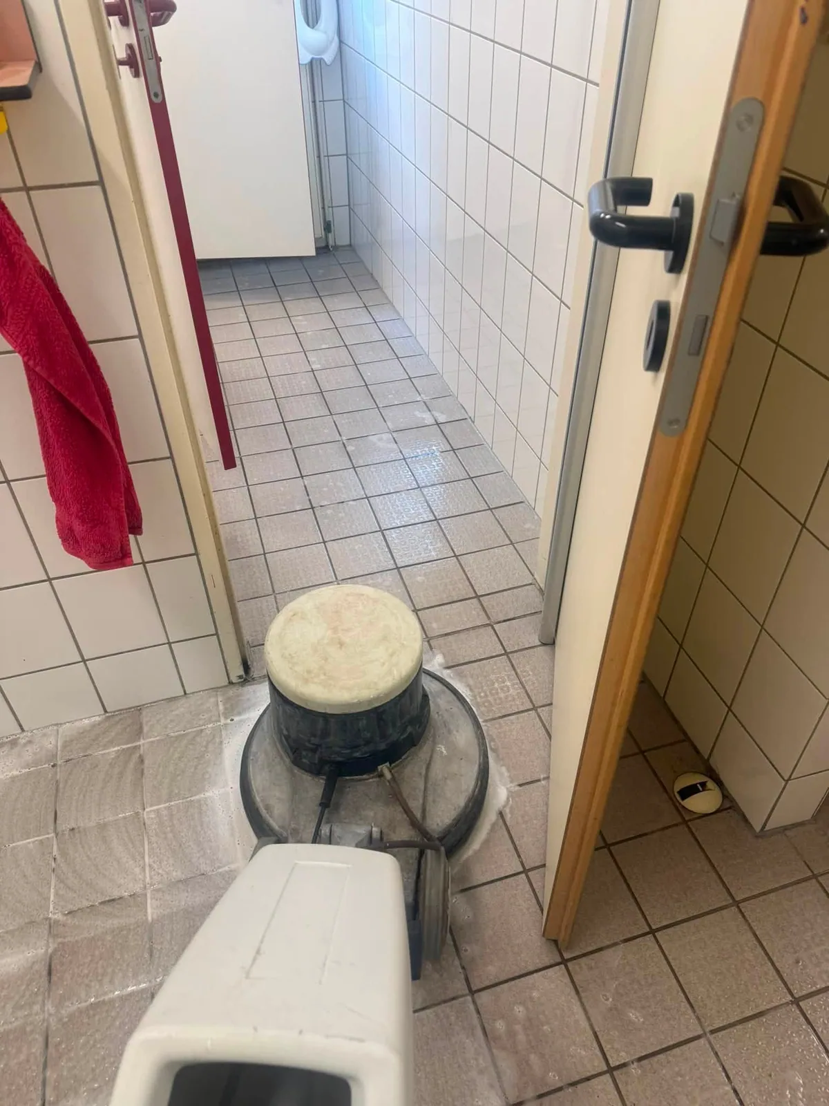 Reinigungsmaschine im Türdurchgang zwischen Fliesen- und Bodenbelag