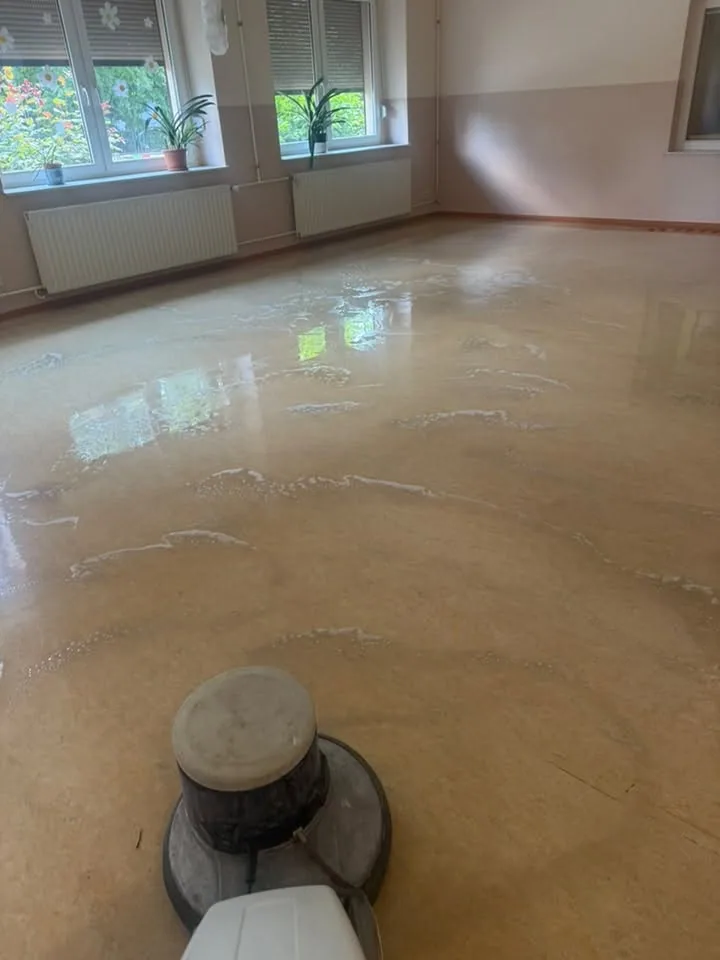 Einscheibenmaschine in einem Gruppenraum, Reinigungslösung auf dem Belag