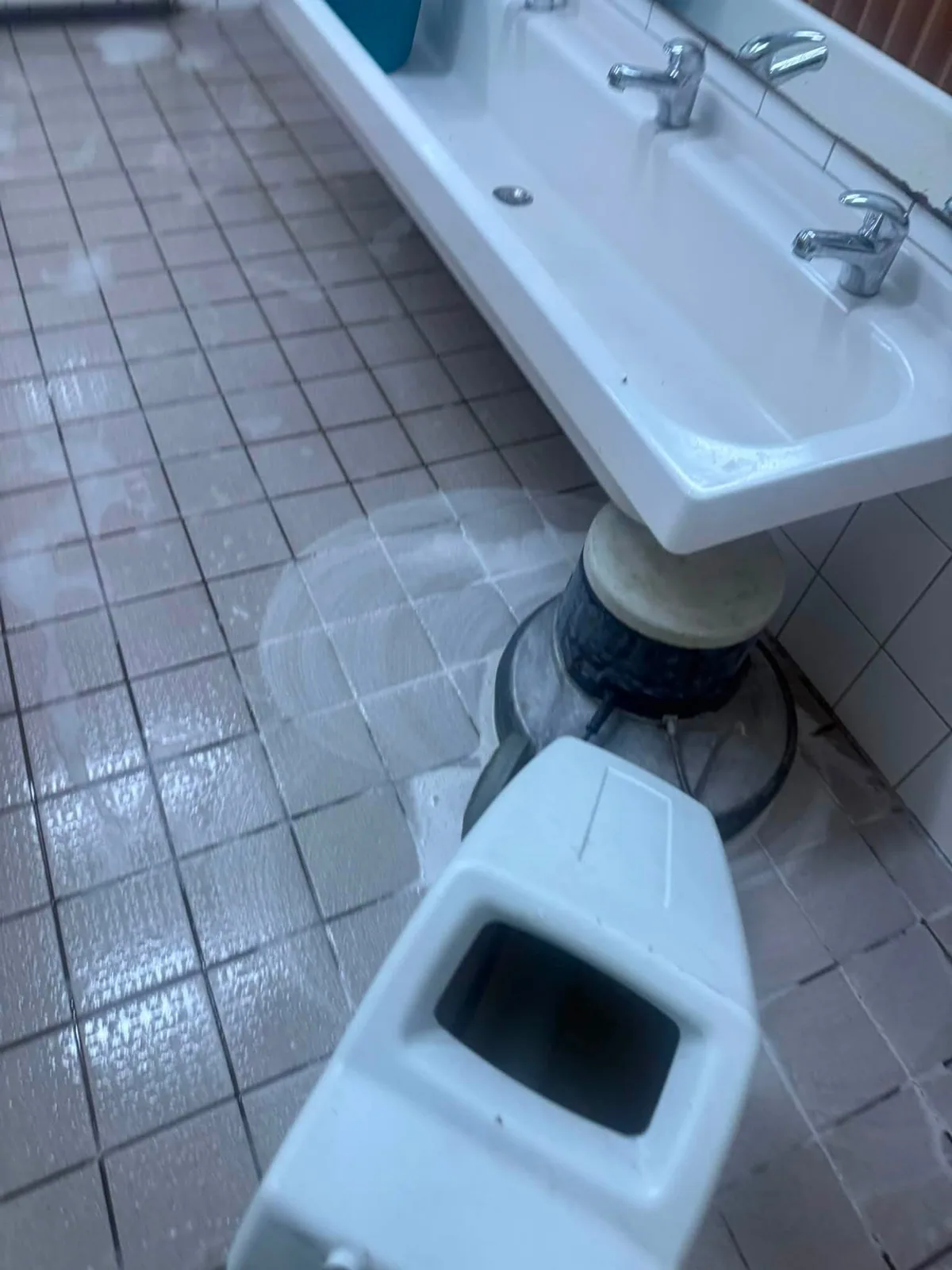 Reinigungsmaschine unter einer Waschrinne im Sanitärbereich