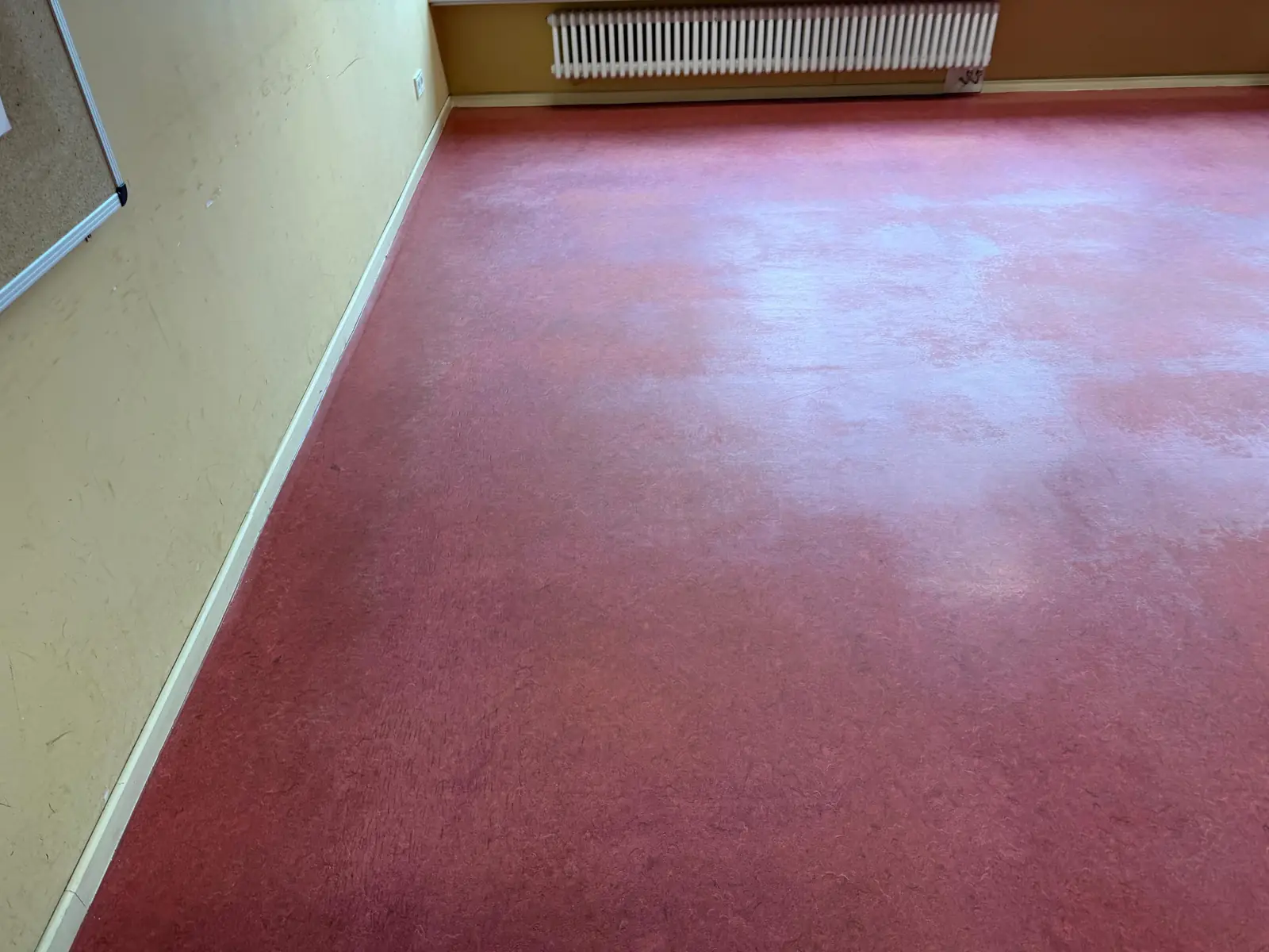 Roter Linoleumboden mit stumpfer, ungleichmäßiger Oberfläche vor der Grundreinigung